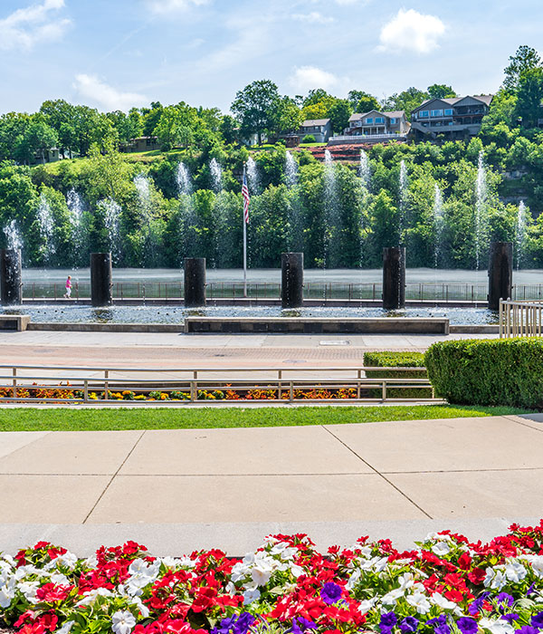 Branson Landing fountains with colorful flowers and scenic hills, representing Roof For Less’s service coverage in Branson, MO.