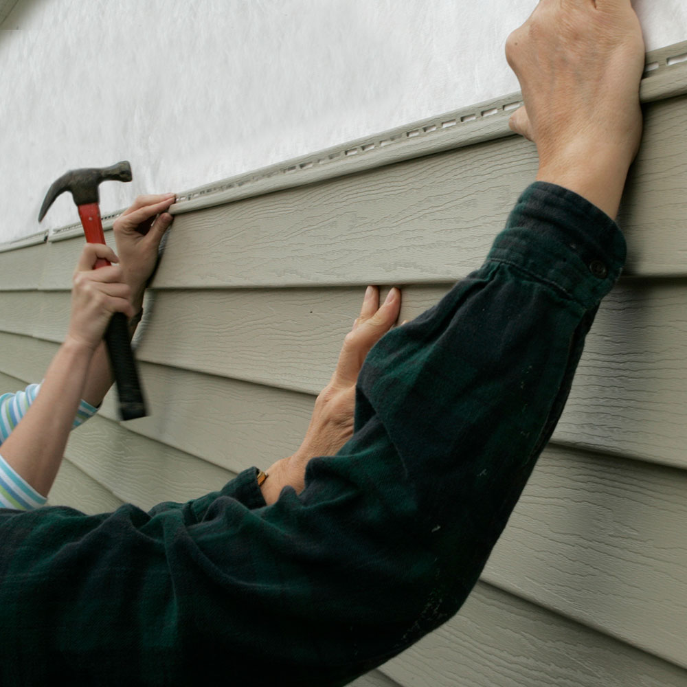 Contractor installing vinyl clapboard siding on a residential home in Springfield, MO, emphasizing precise and professional installation.