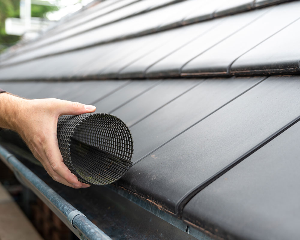 Contractor installing a mesh gutter guard on a residential home in Springfield, MO, highlighting Roof For Less's expert installation services.