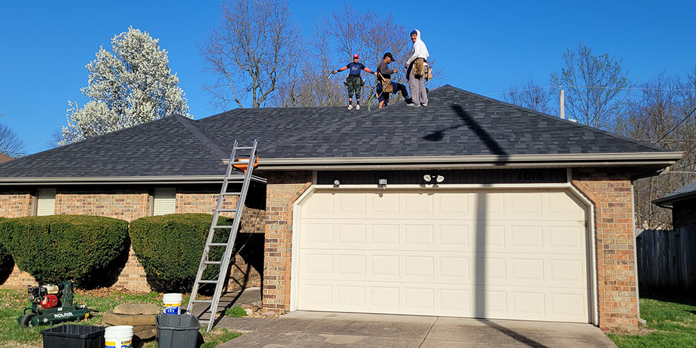 Team of roofers installing new asphalt shingles on a residential home under a clear sky, demonstrating Roof For Less's quality roofing services in Springfield, MO.