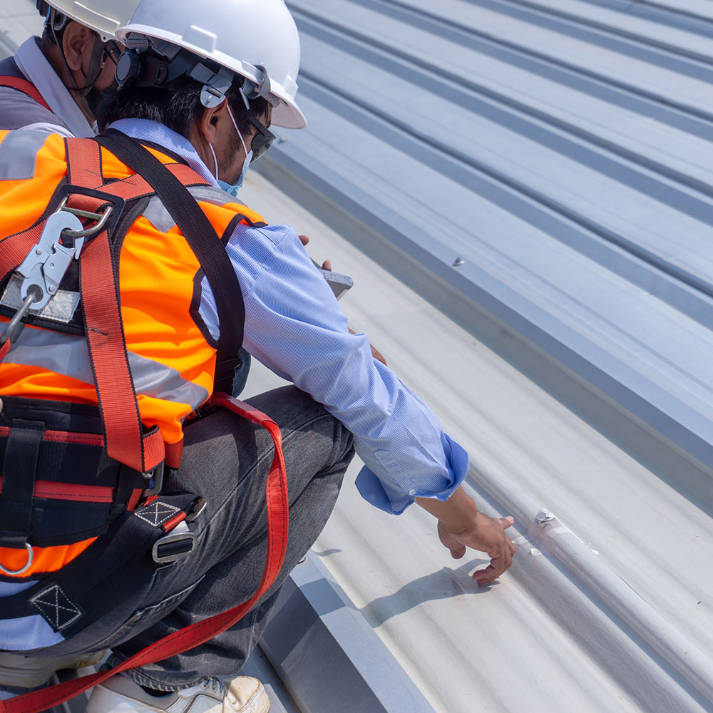 Roofing contractors inspecting storm damage on a metal roof in Springfield, MO, highlighting Roof For Less's reliable storm damage repair services.