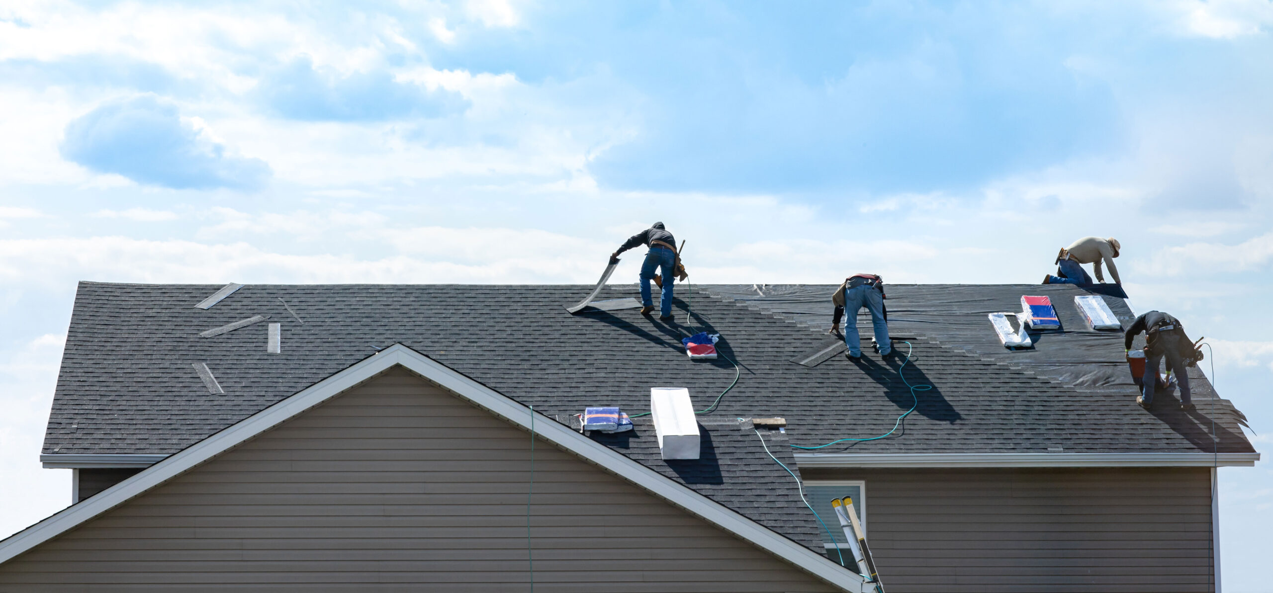 Team of roofers installing new asphalt shingles on a residential home under a clear sky, demonstrating Roof For Less's quality roofing services in Springfield, MO.