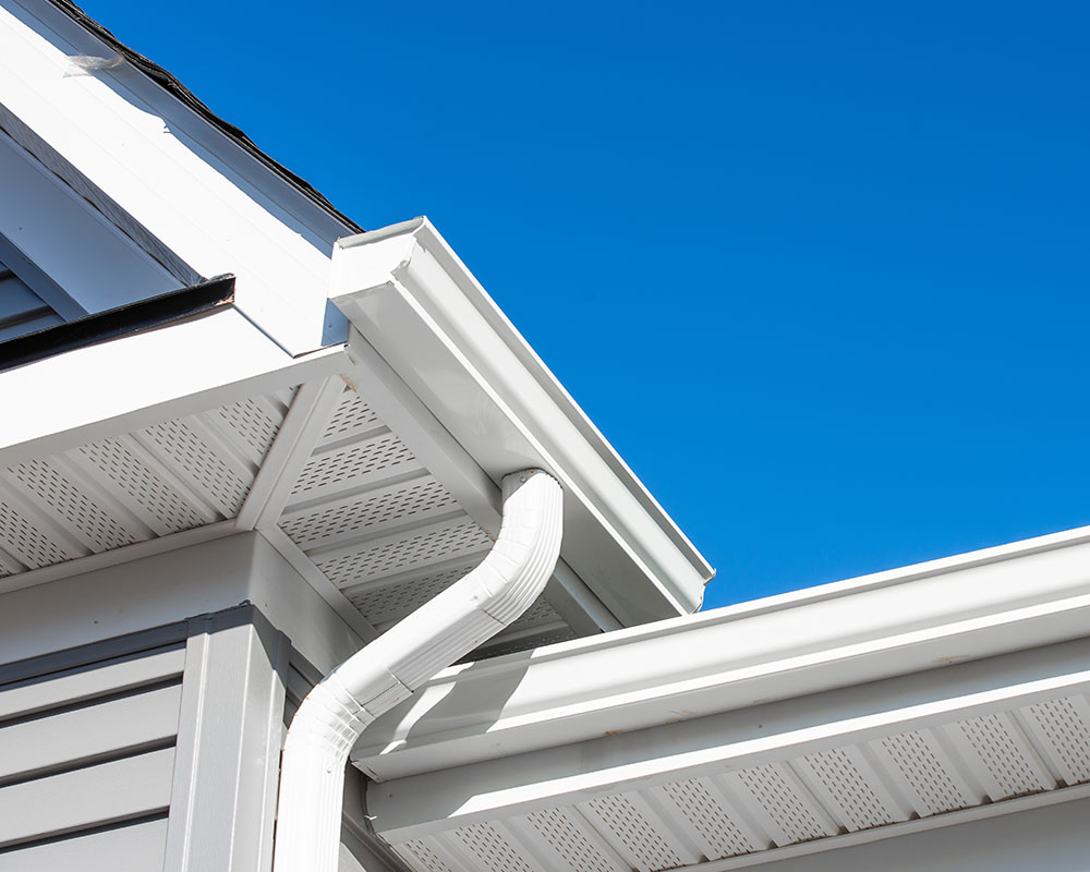 Close-up view of a modern, multi-pitched asphalt shingle roof on a luxury home with detailed gable accents.