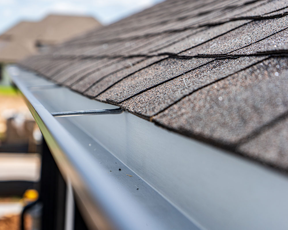 Contractor installing a mesh gutter guard on a residential home in Springfield, MO, highlighting Roof For Less's expert installation services.